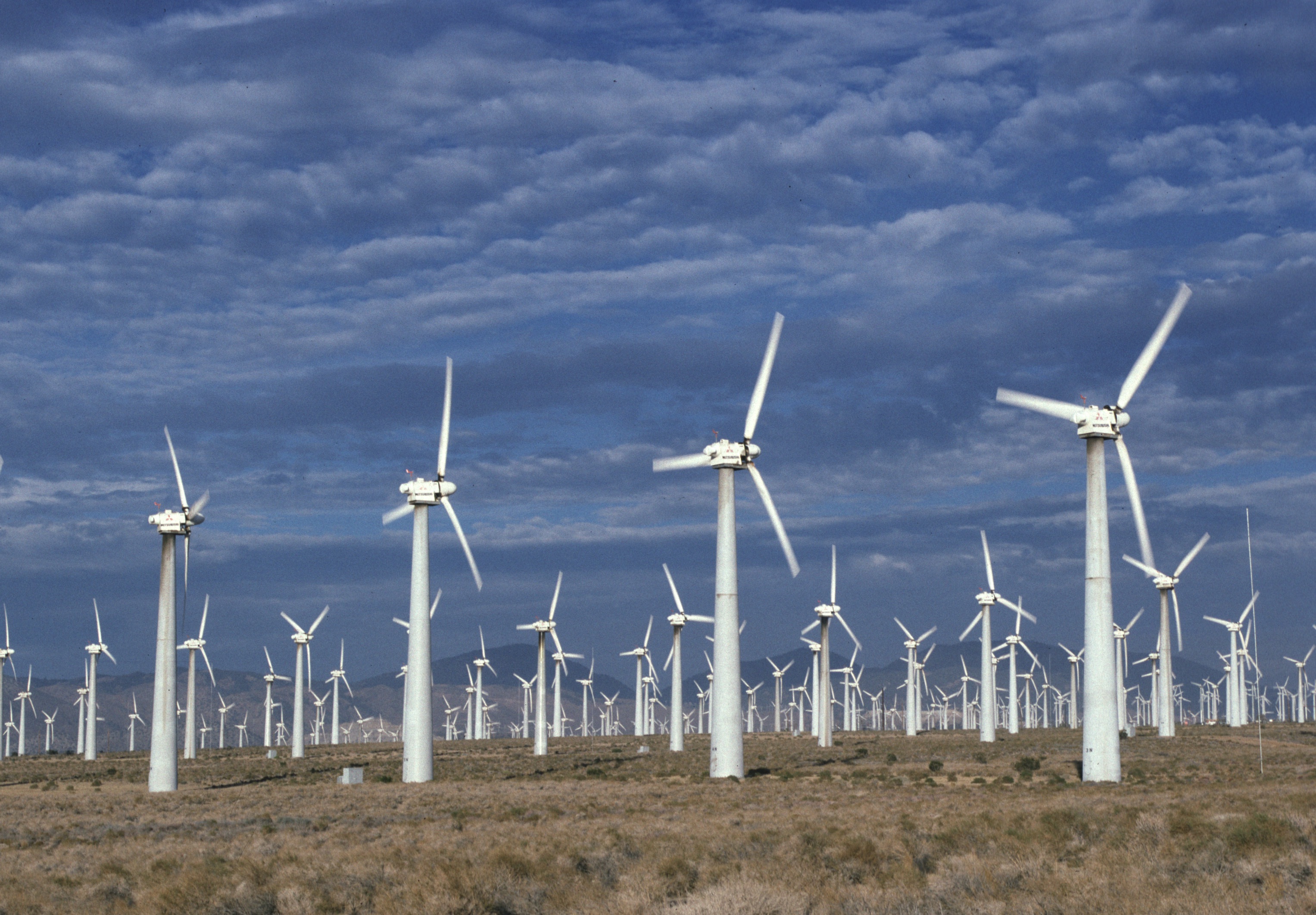 A farm of wind turbines in a field.